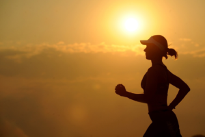 A silhouette of a woman running against the sun.