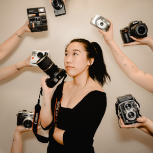 A woman standing between hands holding cameras