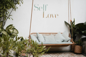 A Swing in Front of a Wall Labeled “Self-Love” and Surrounded by Plants
