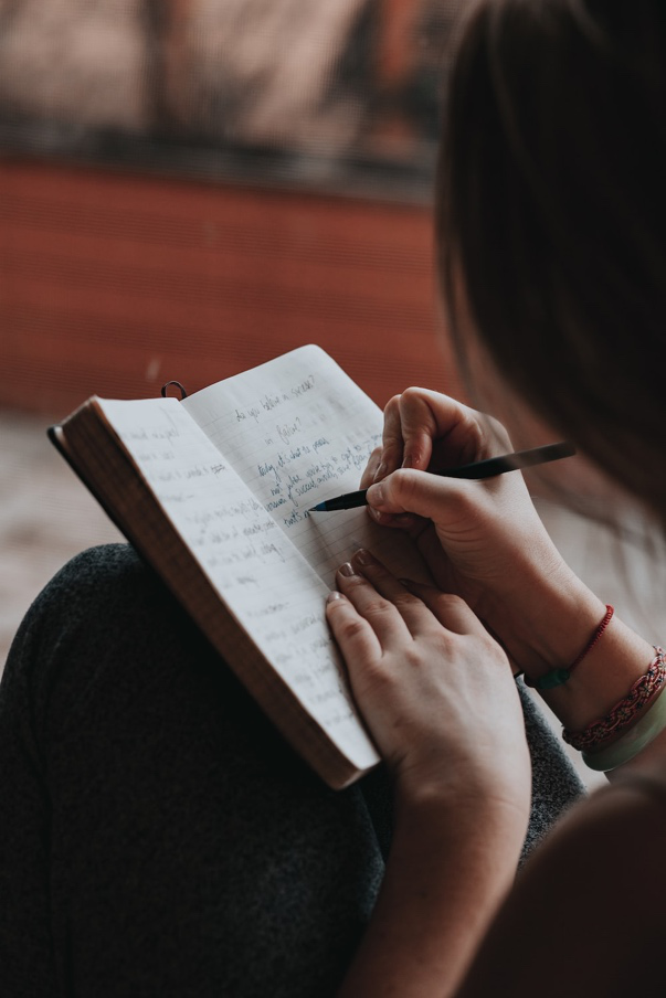 A Woman Jotting Down Her Goals in a Notebook