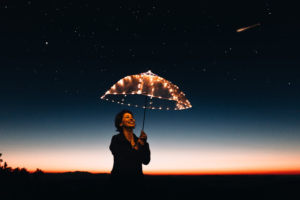 A Grinning Woman Holds an Umbrella with Fairy Lights Under a Starry Sky