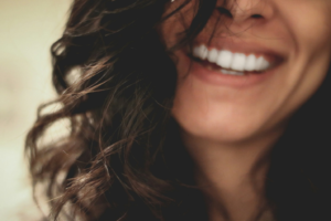 A close-up of a smiling woman’s face with dark curls on either side